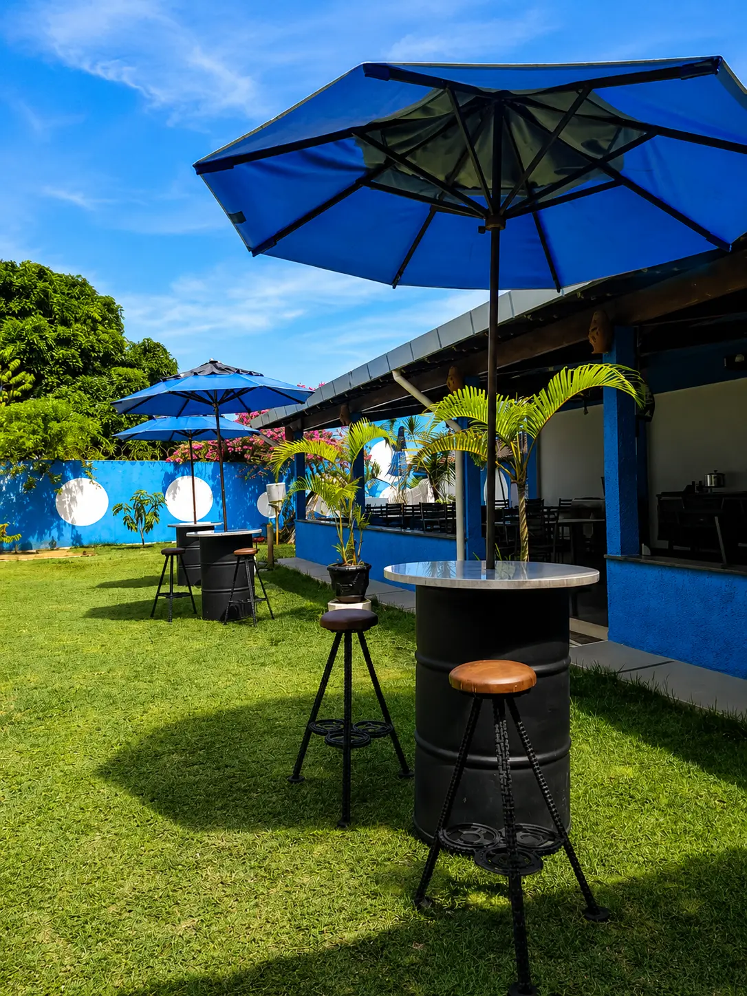 Mesas com guarda-sóis azuis no gramado